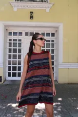 Vestido corto sin mangas, de tejido de punto en color azul marino con efecto jaspeado o tweed en tonos claros. Presenta un corte amplio y relajado, con cuello redondo y bordes en contraste.