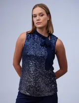 Blusa azul de microtul bordado con lentejuelas, marca Cable & Gauge. Cuello alto en gasa, escote asimétrico y lazo de ajuste.