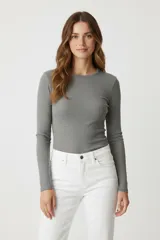 Remera de manga larga confeccionada en algodón de color gris, con cuello redondo y calce ajustado al cuerpo.