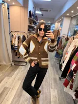 Campera tejida de punto en color marrón con diseño de rombos en tonos celestes y amarillos. Presenta cuello con detalle de corderito, cierre frontal con botones y puños acanalados.