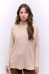 Polera de tejido de punto acanalado en color beige, con cuello alto y mangas largas. Diseño de corte recto y largo medio.