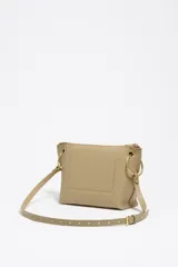 Bolso bandolera de estructura rígida y tamaño mediano confeccionado en piel vacuna. Presenta asa regulable, cierre con cremallera, bolsillo interior y logo metálico de la marca. Incluye un charm decorativo con borlas en el lateral y acabados metálicos.