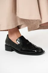 Mocasín de cuero charol negro con diseño enrejillado en la capellada y horma cuadrada.