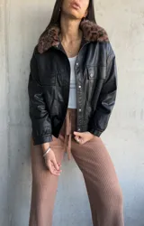 Campera negra de cuero sintético, con cuello de piel sintética con estampado animal print, cierre frontal con botones a presión, bolsillos con solapa en el pecho y corte recto.