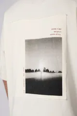 Remera de corte oversize en color crudo, con cuello redondo y mangas cortas. Presenta un pequeño estampado gráfico minimalista en el lado derecho del pecho.