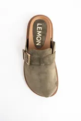 Zueco de gamuza color verde oliva, con diseño cerrado en la parte frontal y hebilla metálica dorada ajustable en el empeine. Presenta una suela de goma dentada en color marrón.