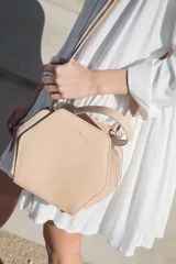 Bandolera color beige con forma geométrica, con correa larga regulable y asa corta.