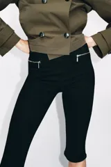 Jeans capri de tiro medio en color negro, con diseño de falsos bolsillos delanteros con cierre metálico y pierna corta.