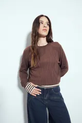 Sweater de punto color negro, con cuello redondo y diseño texturizado con ondas en relieve. Presenta mangas largas y un calce cómodo y holgado.