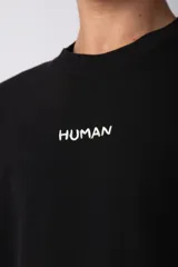 Remera oversize de algodón pesado color azul, con bordado "HUMAN" centrado en el pecho y hombros ligeramente caídos.