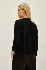 Sweater negro de manga larga con cuello redondo, decorado con apliques brillantes que simulan un degradé o salpicado en la parte superior del pecho y hombros.