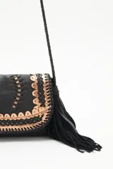 Cartera bandolera negra de cuero con diseño trenzado y apliques dorados en el frente, flecos de cuero en la parte inferior y correa trenzada.