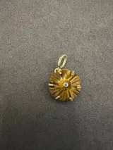 Dije de piedra natural tallada con forma floral, engarzado en metal dorado con una circonia central.