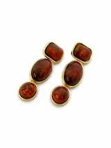 Aros colgantes dorados con tres piedras translúcidas en tonos marrones ámbar de diferentes formas.