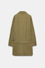 Vestido corto verde militar de cuello solapa y manga larga, con bolsillos de plastrón en el delantero y cierre frontal con cremallera oculta por sopata. Cuenta con un cinturón incorporado del mismo tejido con hebilla metálica y aberturas laterales en el bajo.