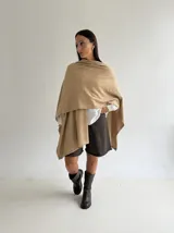 Ruana de tejido de punto trenzado en color crudo, con diseño abierto, corte holgado y mangas amplias tipo kimono.