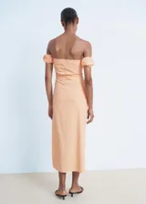 Vestido midi de color durazno, con escote palabra de honor y mangas cortas abullonadas caídas. Presenta un diseño entallado con abertura lateral en la falda y cierre de cremallera lateral.