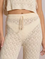 Pantalón de tiro alto con tejido calado y textura labrada, de corte recto con apertura acampanada hacia el ruedo. Cuenta con cintura elastizada y cordón de ajuste con terminaciones de caracoles decorativos.