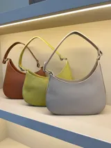 Cartera tipo hobo de cuero con textura granulada, diseño de media luna y asa fija para llevar al hombro.