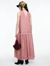 Vestido largo de viscosa en color beige con efecto gastado, diseño sin mangas con escote halter y tira tipo choker para anudar al cuello. Presenta un corte a la altura de la cadera con falda fruncida que aporta volumen y movimiento.