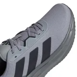 Championes de running Adidas modelo Galaxy 7, color gris con detalles en negro y una franja roja en la entresuela. Presentan capellada de malla transpirable, cierre con cordones y tecnología de amortiguación Cloudfoam en la suela.
