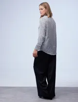 Camisa de satén estampado con diseño de cadenas en blanco y negro. Cuello con solapa, escote en V y abertura central con botones.
