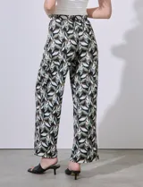 Pantalón largo de seda fría estampada con hojas en tonos verde, blanco y negro. Tiene pretina ancha elastizada.