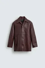 Cazadora de hombre de corte relajado, confeccionada en piel con textura irregular color marrón oscuro (vino/borgoña). Presenta cuello solapa, manga larga con puño abotonado, bolsillos de vivo en cadera, bolsillo interior y cierre frontal con botonadura.