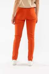 Pantalón de corte slim skinny, color naranja vibrante, con cierre de botón y cremallera frontal, y bolsillos laterales.
