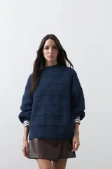 Sweater de punto color marrón chocolate, con cuello redondo, mangas largas abullonadas y puños ajustados. Presenta un diseño de textura acanalada horizontal y silueta relajada.