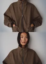 Chaqueta de diseño recto con estampado de pata de gallo, cuello alto y manga larga con puños elásticos. Cuenta con cierre delantero de cremallera y dos bolsillos con solapa en la parte delantera.