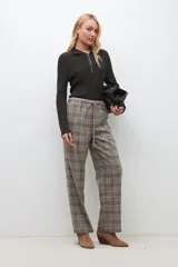 Pantalón largo de corte recto con estampado de cuadros escoceses en tonos beige, marrón y negro. Tiene cintura elástica con cordón ajustable.