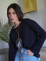 Collar con dije de piedra ágata blanca y marrón, con forma circular irregular y agujero en el centro. El dije está sujeto con un cordón fino de cuero marrón.