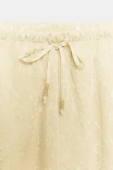 Shorts de tiro medio confeccionados en tejido jacquard con mezcla de cupro, en color beige. Presentan cintura elástica ajustable con cordones y detalle de aplicación de encaje a tono en el ruedo.