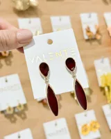 Caravanas colgantes de fiesta doradas con detalles en esmalte bordó, formadas por una pieza superior en forma de lágrima y una pieza inferior alargada.