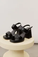 Sandalias de cuero negro con plataforma delantera, taco ancho y tira ajustable en el talón.