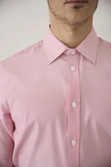 Camisa de vestir blanca de manga larga, con cuello clásico y cierre frontal de botones. Presenta un corte entallado que se adapta a la silueta.