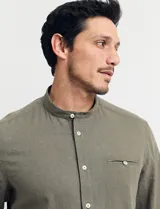 Camisa de cuello mao y manga larga, confeccionada en una mezcla de lino y algodón. Presenta un diseño de corte recto con botones en tono natural y un bolsillo pequeño en el pecho.