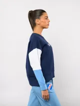 Buzo de cuello redondo con diseño de bloques de color en rojo, blanco y azul. Presenta el logo de Umbro y el escudo del Club Nacional de Football bordados en el pecho.