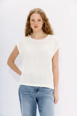 Remera blanca de lino con cuello redondo, mangas cortas y detalles de brillos plateados.