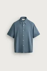 Camisa de corte regular fit confeccionada en mezcla de algodón y lino, en color azul grisáceo. Cuenta con cuello solapa, manga corta y cierre frontal de botonadura.