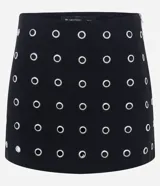 Short pollera corto de bengalina, con diseño ajustado y detalle de ojalillos metálicos distribuidos por toda la prenda. Cuenta con cierre lateral invisible.