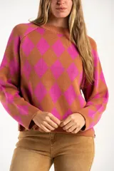 Sweater de punto con diseño de rombos en colores fucsia y tostado, cuello redondo y mangas largas.