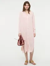 Camisa larga de corte oversize, color rosado, con cuello camisero, cierre frontal con botones y mangas largas.