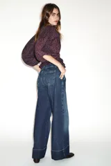 Jeans de tiro bajo con pernera recta y bajo con vuelta. Cuenta con cinco bolsillos y cierre frontal con cremallera y botones.