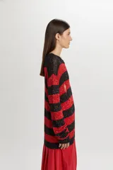 Buzo tejido de punto con diseño de rayas horizontales en negro y rojo, con acabado brillante de lentejuelas y detalles desgastados.