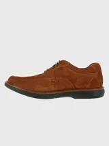 Zapato de estilo casual confeccionado en cuero gamuzado color marrón, con cierre de cordones y suela de goma EVA negra. Presenta costuras reforzadas en la puntera y detalle de logo grabado en el lateral.