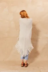 Chal triangular de tejido de punto color crudo con flecos en el borde inferior.