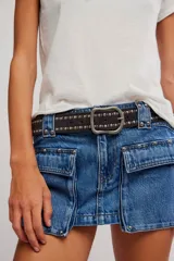 Minifalda de denim azul de tiro bajo, con bolsillos cargo frontales con tapa, detalles de tachas metálicas y costuras pespunteadas.