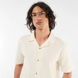 Camisa de manga corta color blanco con diseño texturizado, cuello cubano y cierre frontal de botones.